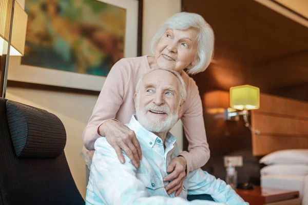 Life partners. Elderly couple in a nice room looking happy and peaceful