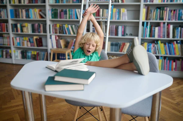 Yawning Blond Boy Sitting Chair His Arms Raised Feet Put — Stock Photo, Image