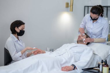 Beauty procedures. Two professionals working with the client in the beauty salon