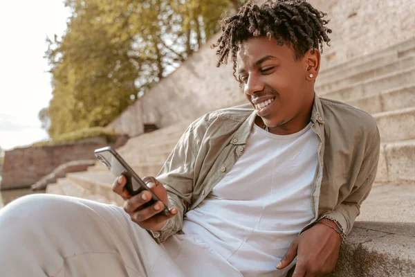 Leisure Dark Skinned Guy Looking Interestedly Smartphone Reclining Resting Nature — Stok Foto