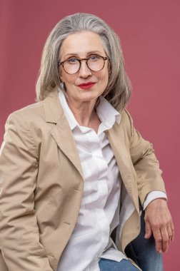 Woman in studio. Good-looking mid aged woman in a beige jacket looking at the camera