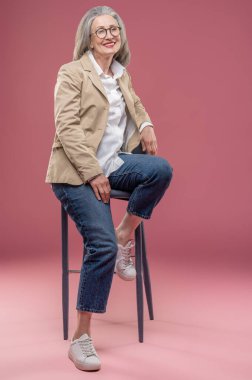 Elegant woman. Elegant mature woman in beige jacket sitting on a chair