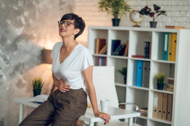 Menopause. Mature short-haired woman suffering from pains in stomach
