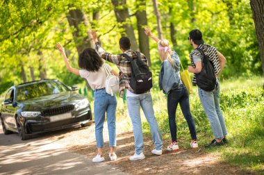 Hitchhiking. Group of young people hitchiking on the road