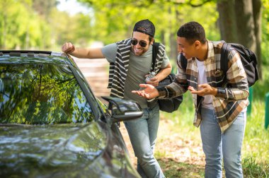 Waiting for the car. Young men stopping the car on the forest road
