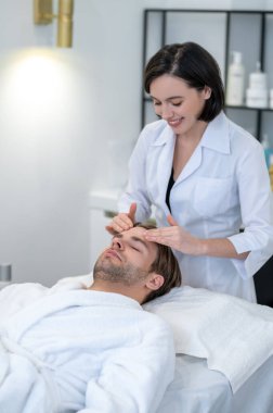 Face massage. Female professional doing face massage to a male client