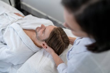 Neck massage. Man lying on a couch and having neck massage
