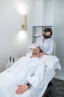 Neck massage. Man lying on a couch and having neck massage