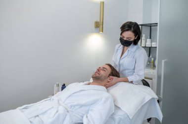 Beauty procedures. Female specialist in a protective mask working with a customer in a beauty salon
