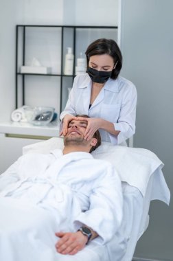 Beauty procedures. Female specialist in a protective mask working with a customer in a beauty salon