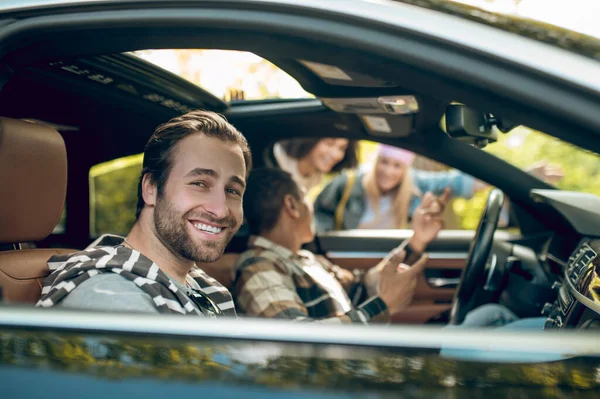 Hitchhikers. Smiling men in a car talking to girls on the road