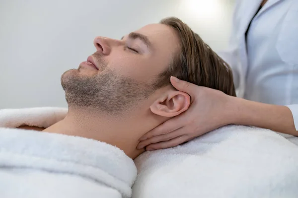 Neck massage. Man lying on a couch and having neck massage