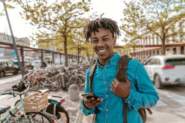 All Excellent Smiling African Guy Smartphone Backpack Looking Camera Confidently — Stok Foto