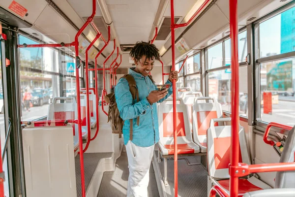 Bus Ride Cheerful Dark Skinned Guy Looking Smartphone Holding Handrail — Stok Foto