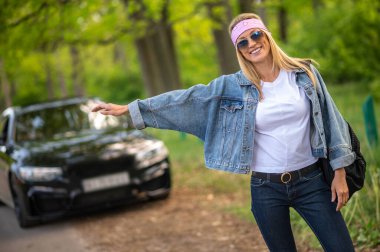 Hitchhiker. Blonde young woman stopping the care on the countryside road