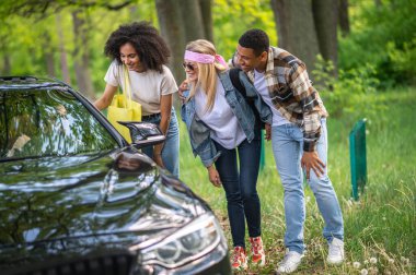Way to the city. Group of young people stopping the car in the forest