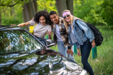 Way to the city. Group of young people stopping the car in the forest