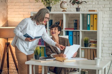 Working on project. Two businesswomen discussing project details and looking involved