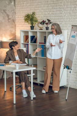 Presentation. Good-looking woman presenting something at the flipchart while her colleagues listening