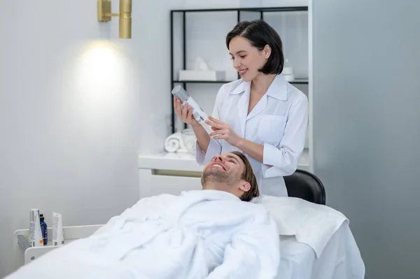 Beauty salon. Young woman in lab coat working with a customer in a beauty salon