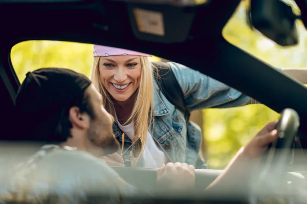 Showing the way. Blonde woman showing the way to a man in a car