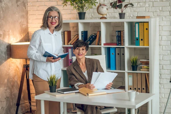 Working on project. Two businesswomen discussing project details and looking involved