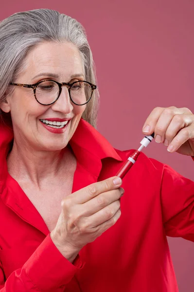 Makeup Woman Red Bright Shirt Holding Lip Gloss Looking Contented — Stok Foto