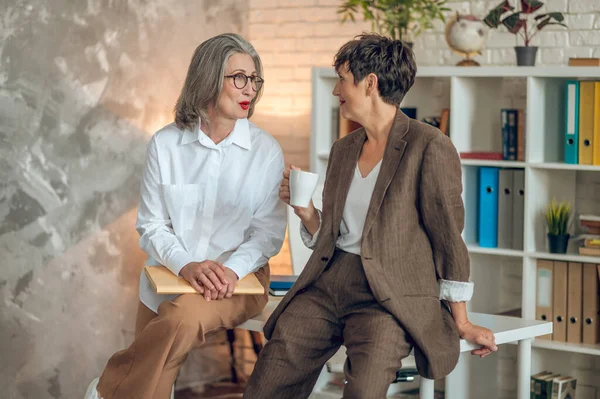 Офисе Две Женщины Разговаривающие Офисе Выглядящие Вовлеченными — стоковое фото