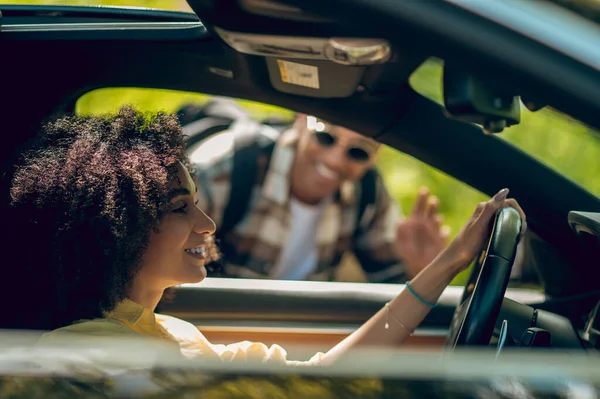 Hitchhiker. Young man and woman talking on the road and smiling
