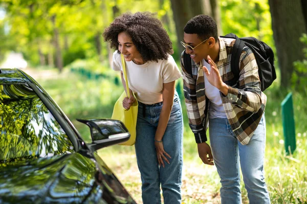 On the way to the city. Dark-skinned couple looking excited while hitchhiking on a countryside road
