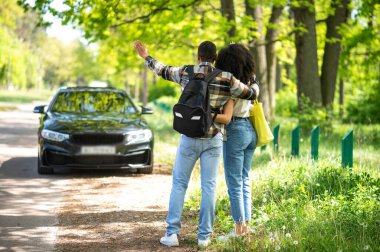 On the road. Young couple hitchhiking on the road on a sunny day