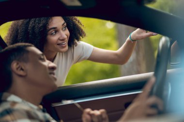 Showing the way. Young woman showing the way to a car driver and smiling
