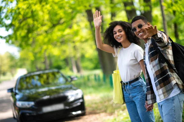 On the road. Young couple hitchhiking on the road on a sunny day