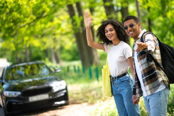 Waiting for the car. Smiling young couple waiting for the car and looking excited