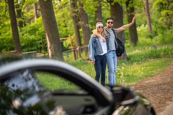 Adventure. Two people trying to stop the car in the forest and looking joyful