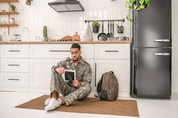 Despondent Young Military Man Sitting Kitchen Floor Looking Framed Photograph — Stockfoto