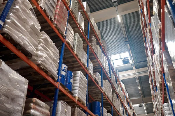 Numerous rows of shelves with packaged wares stacked on the pallets in the warehouse area