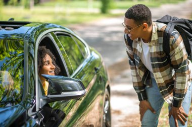 Passenger. African american man in plaid shirt asking a female driver to take him to the city