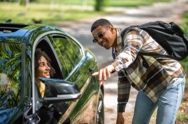 Passenger. African american man in plaid shirt asking a female driver to take him to the city