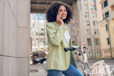 Young woman in the street. Curly-haired pretty woman with a bike in the street