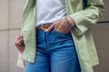 Casual style. Close up picture of a woman near the wall