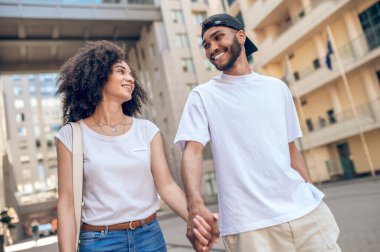 Hand in hand. Young cute couple walking in the street and holding hands