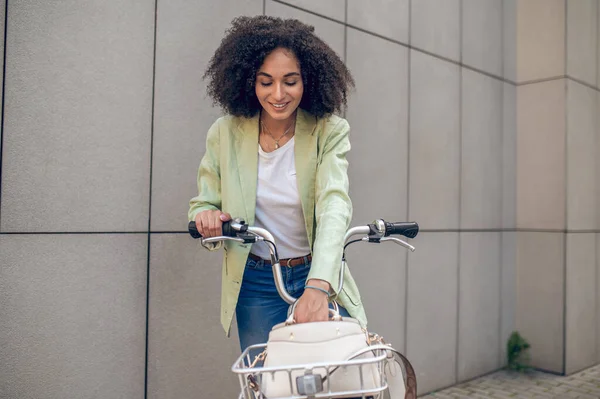 Young woman in the street. Curly-haired pretty woman with a bike in the street