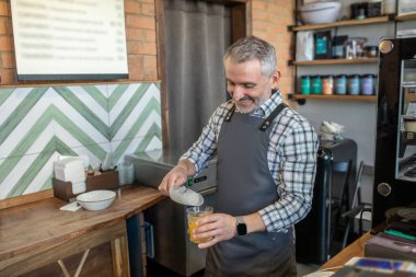 Ice for juice. Man in plaid shirt putting ice to the glass with juice