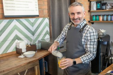 Ice for juice. Man in plaid shirt putting ice to the glass with juice