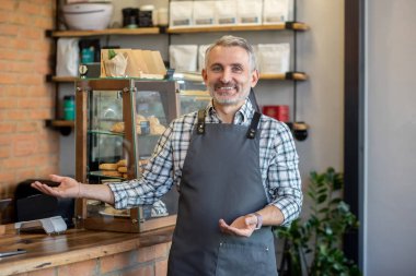 Good day. Cafe owner standing near the counter and looking contented