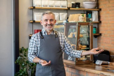 Good day. Cafe owner standing near the counter and looking contented