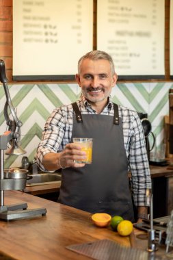 Orange fresh. Man in plaid shirt standing with a glass of orange fresh
