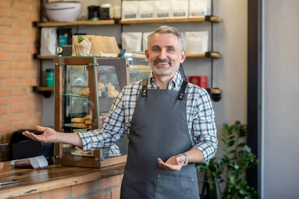 Good day. Cafe owner standing near the counter and looking contented
