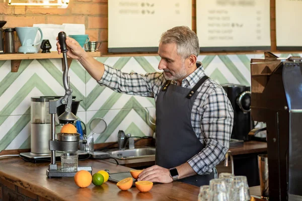 Fresh juice. Man in plaid shirt cutting fruits and preparing fresh juice